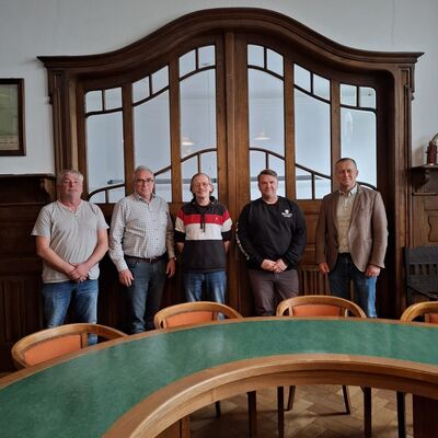Die beiden Mitarbeiter stehen zusammen mit dem B&uuml;rgermeister, dem Abteilungsleiter und dem Personalratsmitglied nebeneinander im Ratssaal und l&auml;cheln in die Kamera.